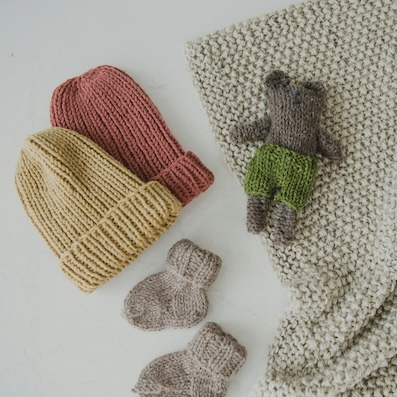 Picture of crochet beanie and socks for a child with a crochet bear and blanket 
                on the side.