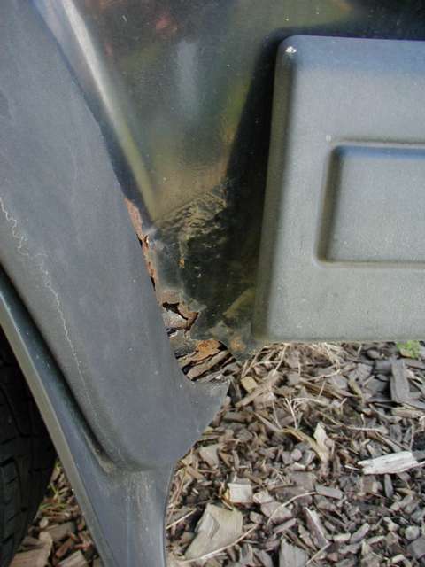 behind rear wheel - driver's side